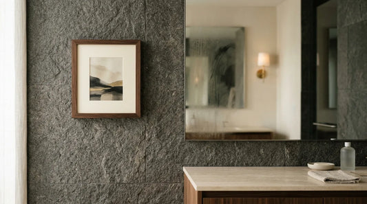 A small framed picture on the wall of a calm modern bathroom with stone tile