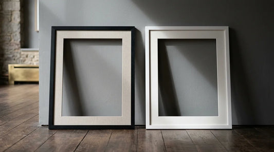 A black frame and a white frame leaning against a grey wall