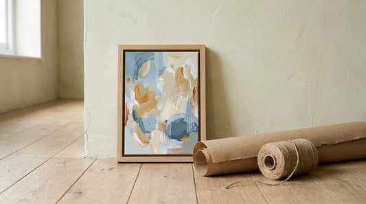 A small framed original abstract painting leaning against a pale wall with kraft wrapping paper and twine, an original art gift under $200 from VanArtHub