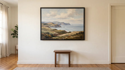 Original oil landscape painting in a black frame hanging on a living room wall above a wooden side table