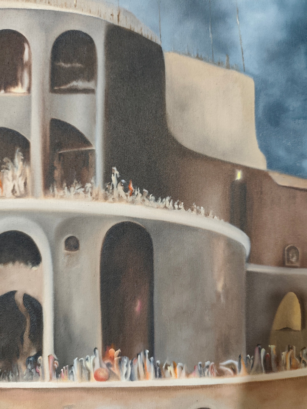 Detail of Why 12? by Melina Ghaemi - the upper tiers of the structure against a dark blue storm sky, rows of tiny figures along the ledges and arched openings cut into the walls.
