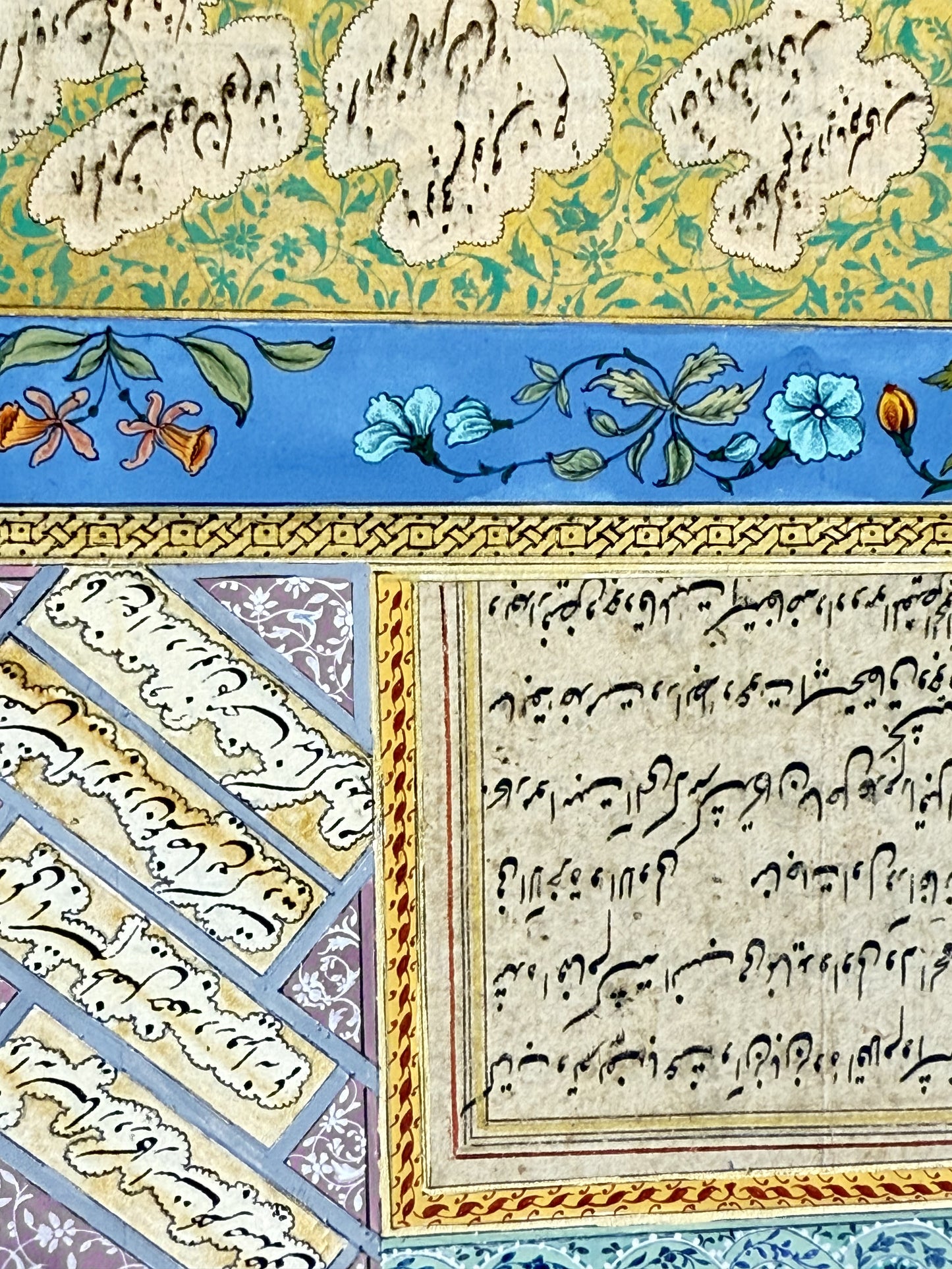 Detail of the calligraphy panels - nasta'liq written in cloud-shaped reserves on a gold ground scattered with turquoise scrollwork, a cobalt blue border painted with turquoise blossoms and orange lilies, and diagonal chalipa couplets on a lilac ground below. Muraqqa': The Gold Shamseh, Kamal al-Din Ghotb.