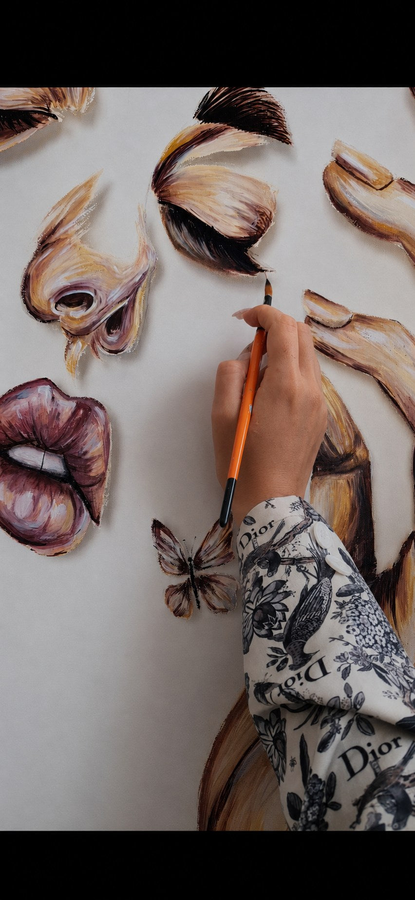 Threads of Becoming by Mahdiye in progress: the artist painting the lash line of a closed eye, with the nose, lips, butterfly and a hand nearby