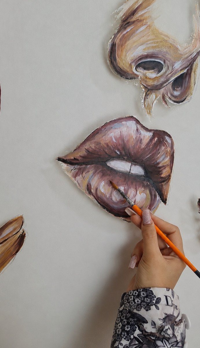 Threads of Becoming by Mahdiye in progress: the artist's hand with an orange brush painting highlights on the parted lips, below the painted nose